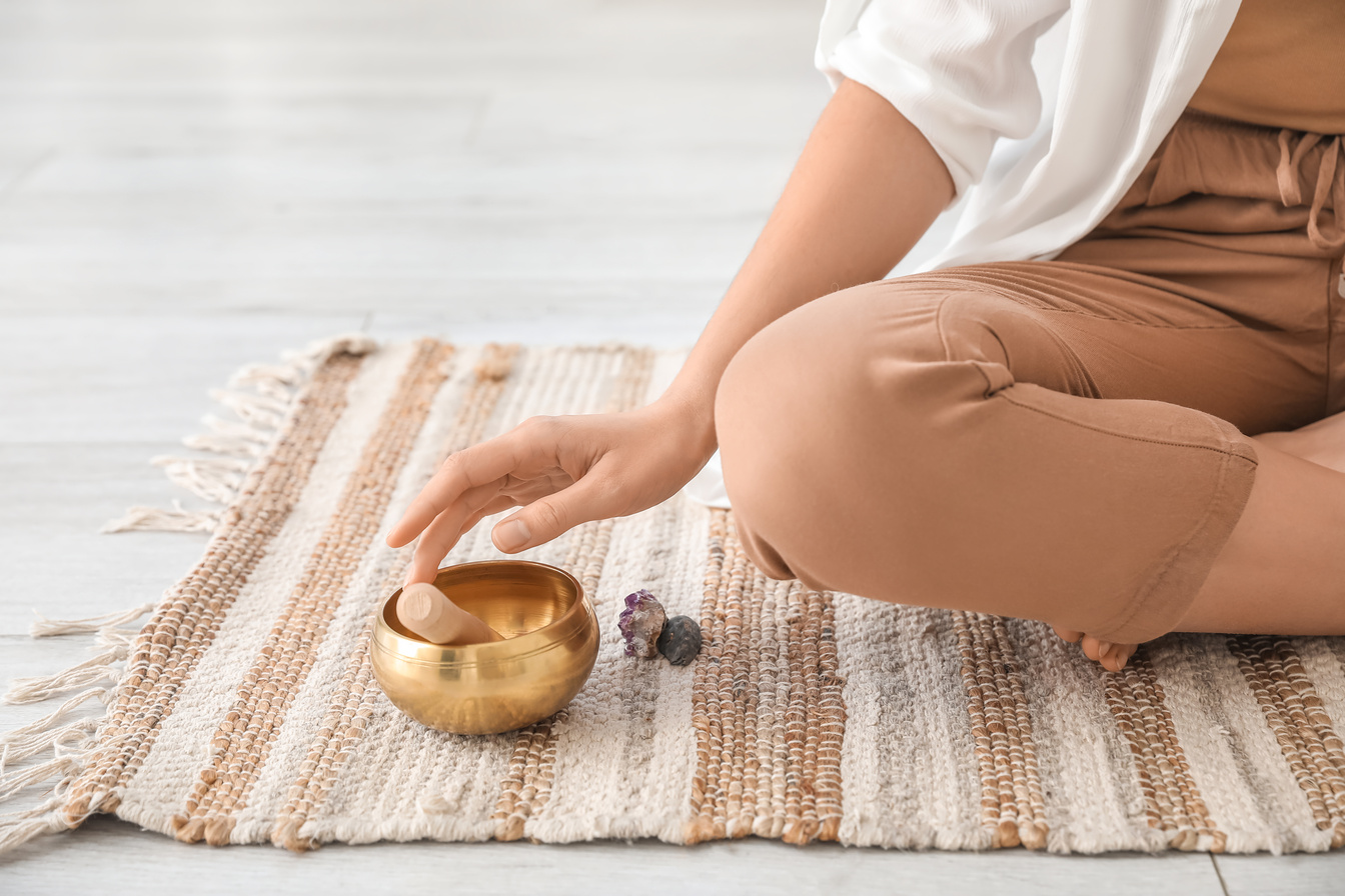 Young Woman Using Tibetan Singing Bowl at Home, Closeup